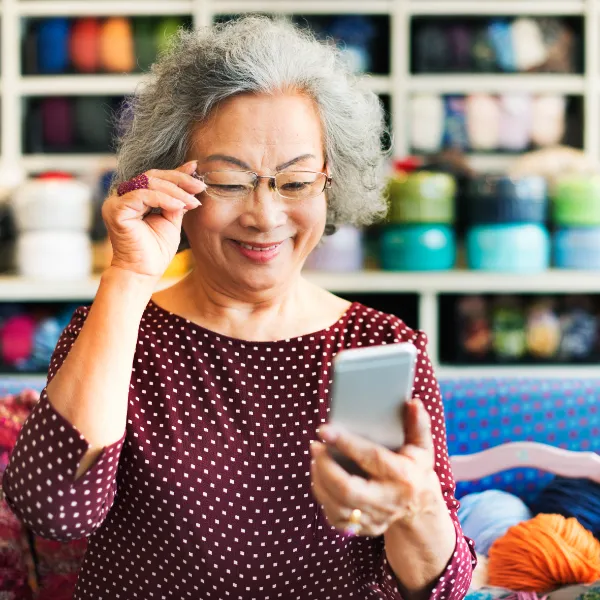 StockImage Carla happy looking at iphone phone in yarn store square crop 600px 5 18 23